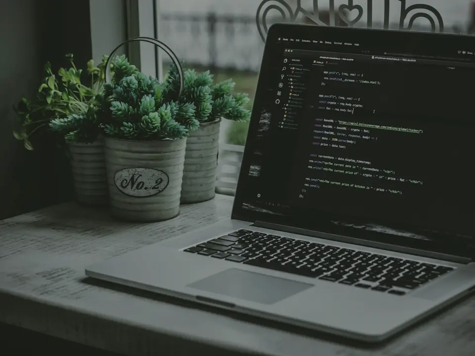 Portátil abierto con código en pantalla sobre una mesa de trabajo del estudio