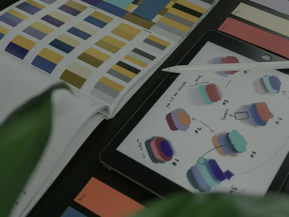 Muestrario de color impreso junto a un boceto de sistema visual sobre una mesa de estudio